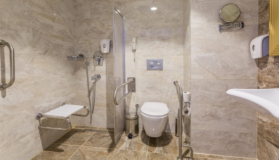 Future-ready curbless shower with grab bars, fold-down seat, and handheld sprayer