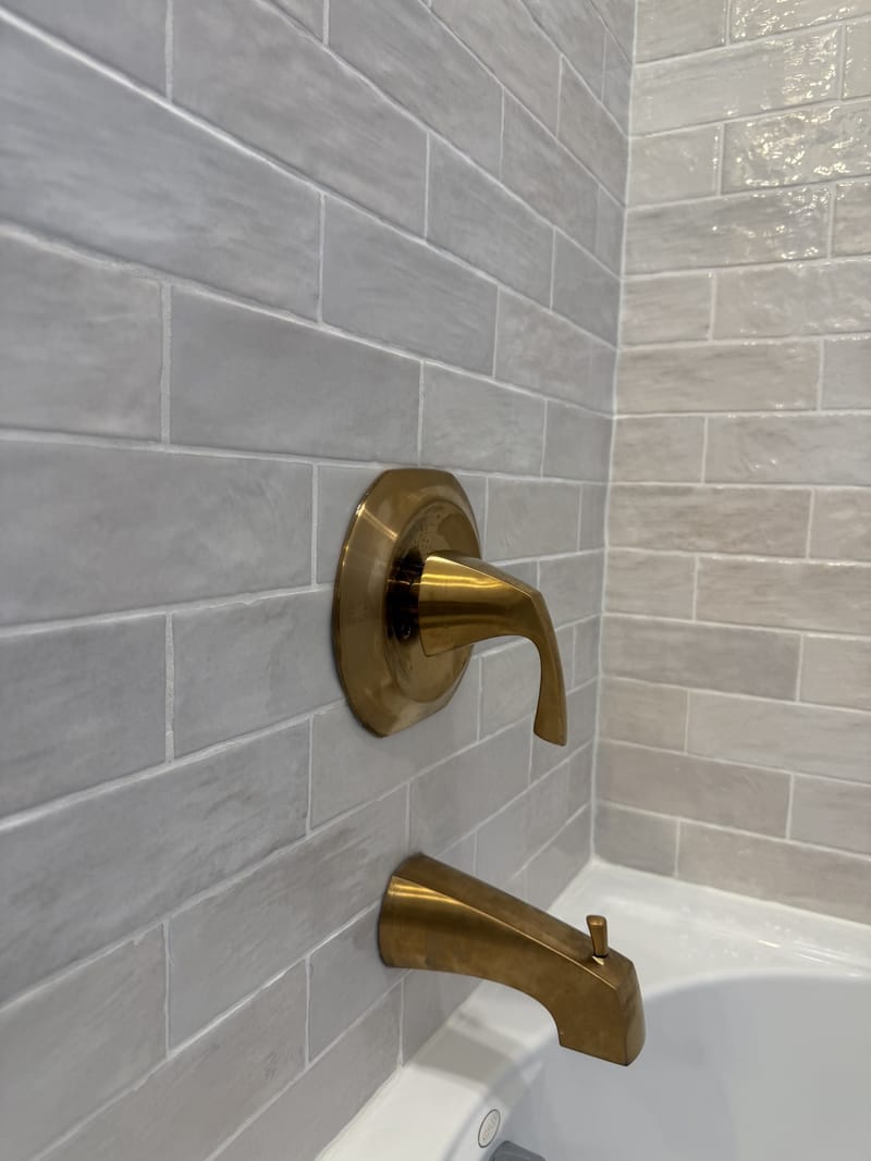Brushed brass tub spout and valve trim on handmade-look tile in a Sacramento bathroom remodel