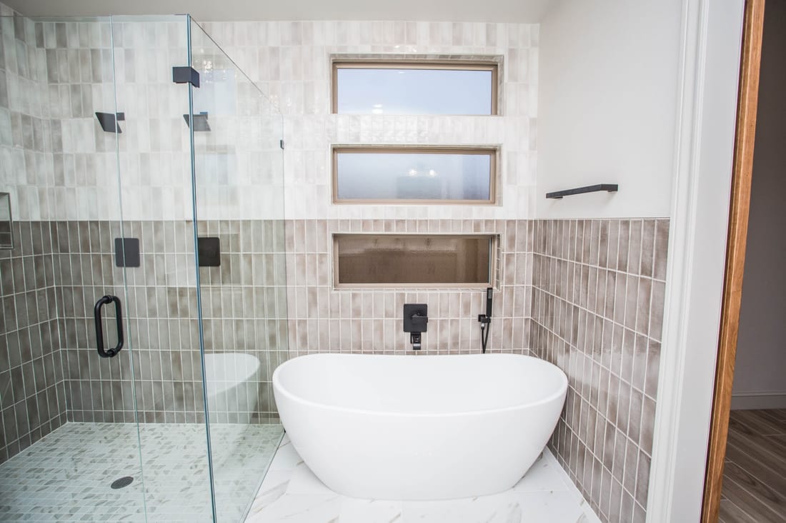 Sacramento bathroom remodel — glass walk-in shower and freestanding tub with two-tone stacked tile and matte black fixtures