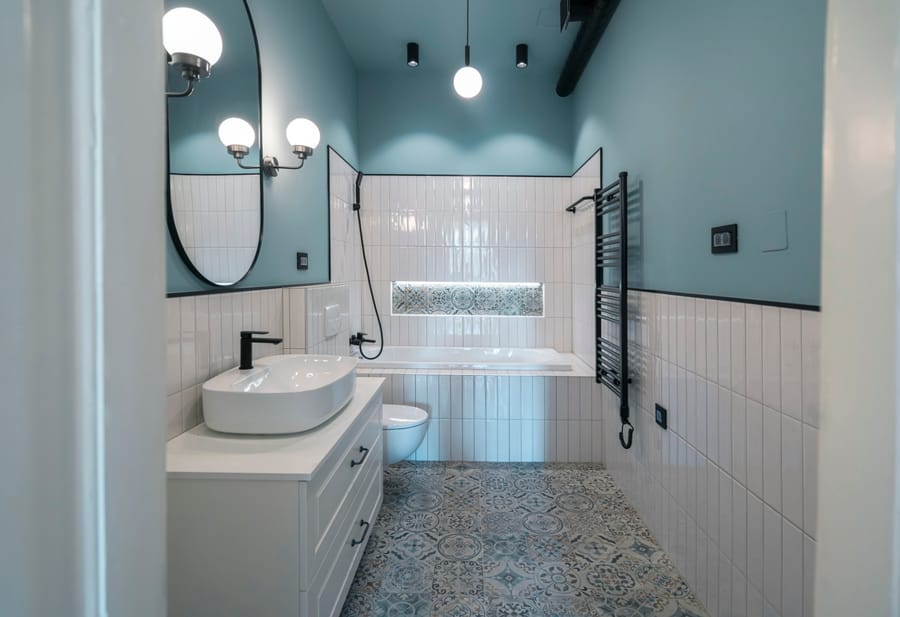 Teal bathroom remodel with vertical stack tile, patterned tile floor, and matte black fixtures
